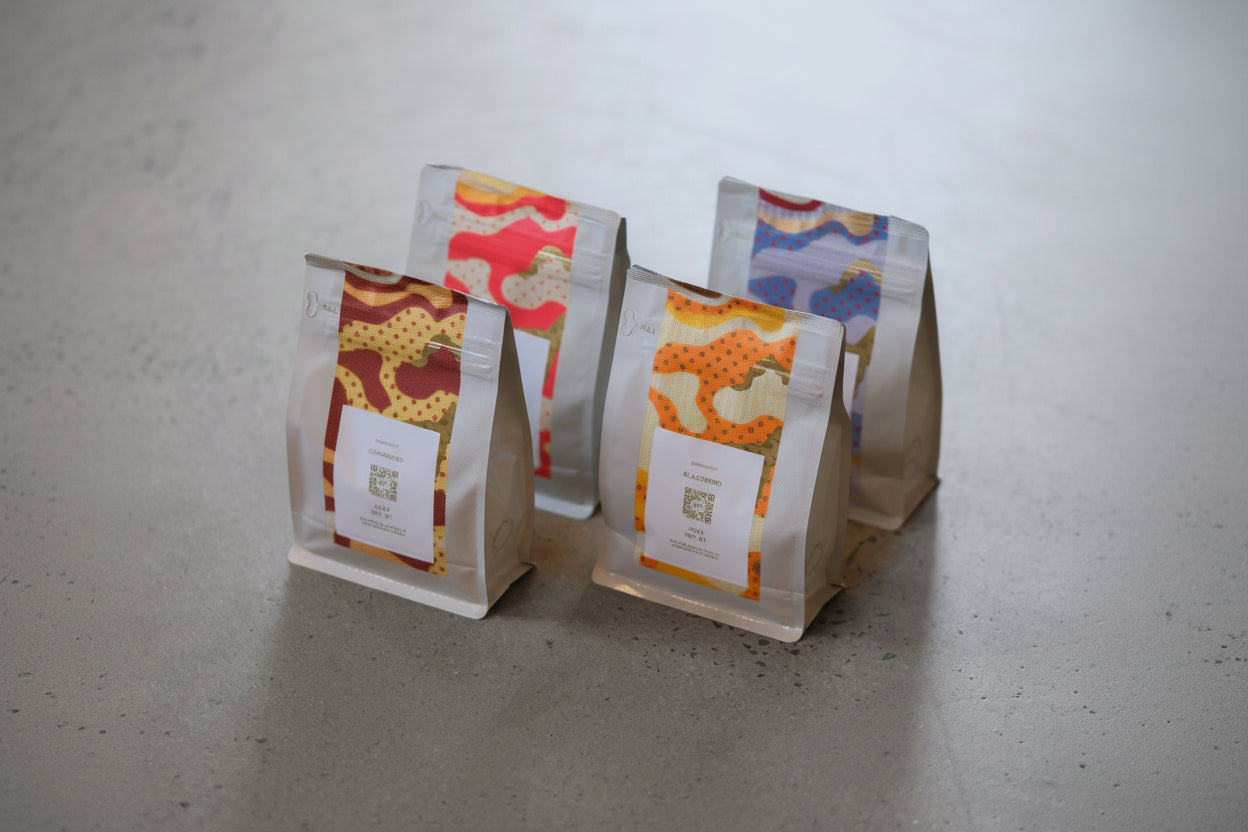 Five coffee bags with colorful patterns on a gray surface